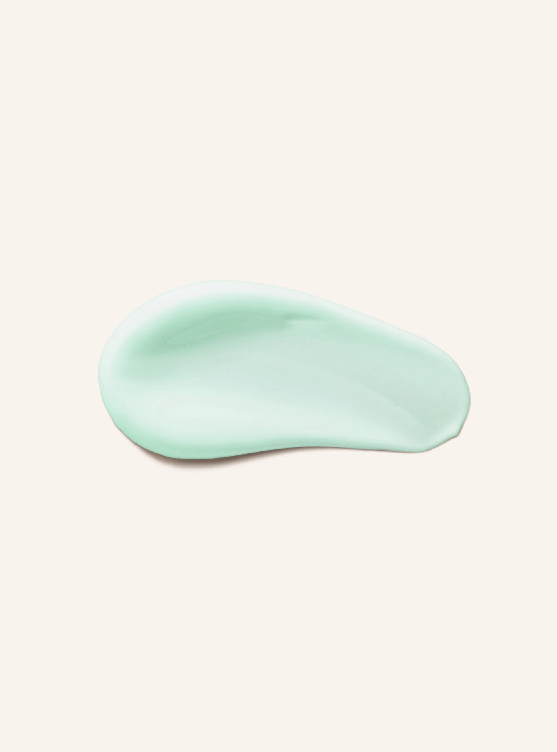 A smooth, glossy swatch of pale mint green cosmetic cream or gel, presented as a swatch on a solid, warm off-white background.