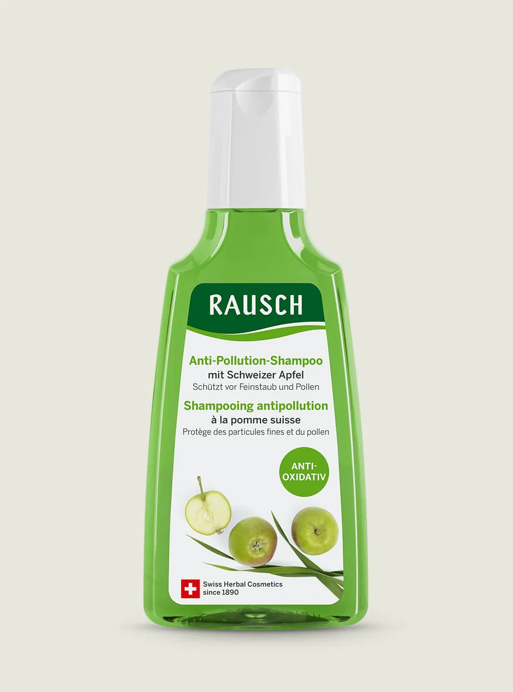 A bottle of Rausch Anti-Pollution Shampoo with green apple scent, featuring a translucent green bottle, white cap, and a white label with green apple graphics, set against a light beige background.