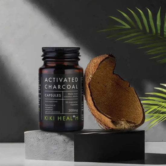 KIKI Health activated charcoal capsules with a coconut on a dark background