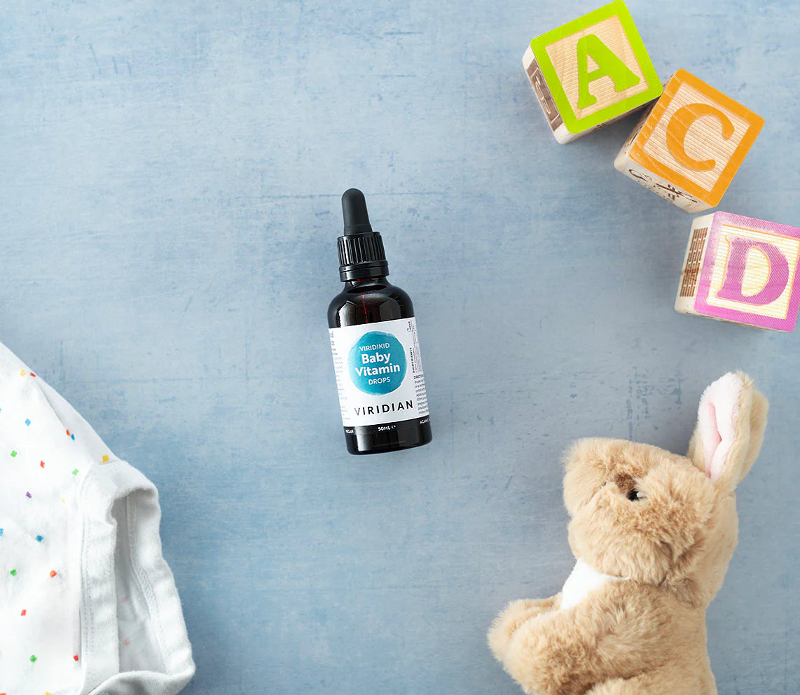 Baby vitamin bottle with colorful blocks and a teddy bear on a blue background