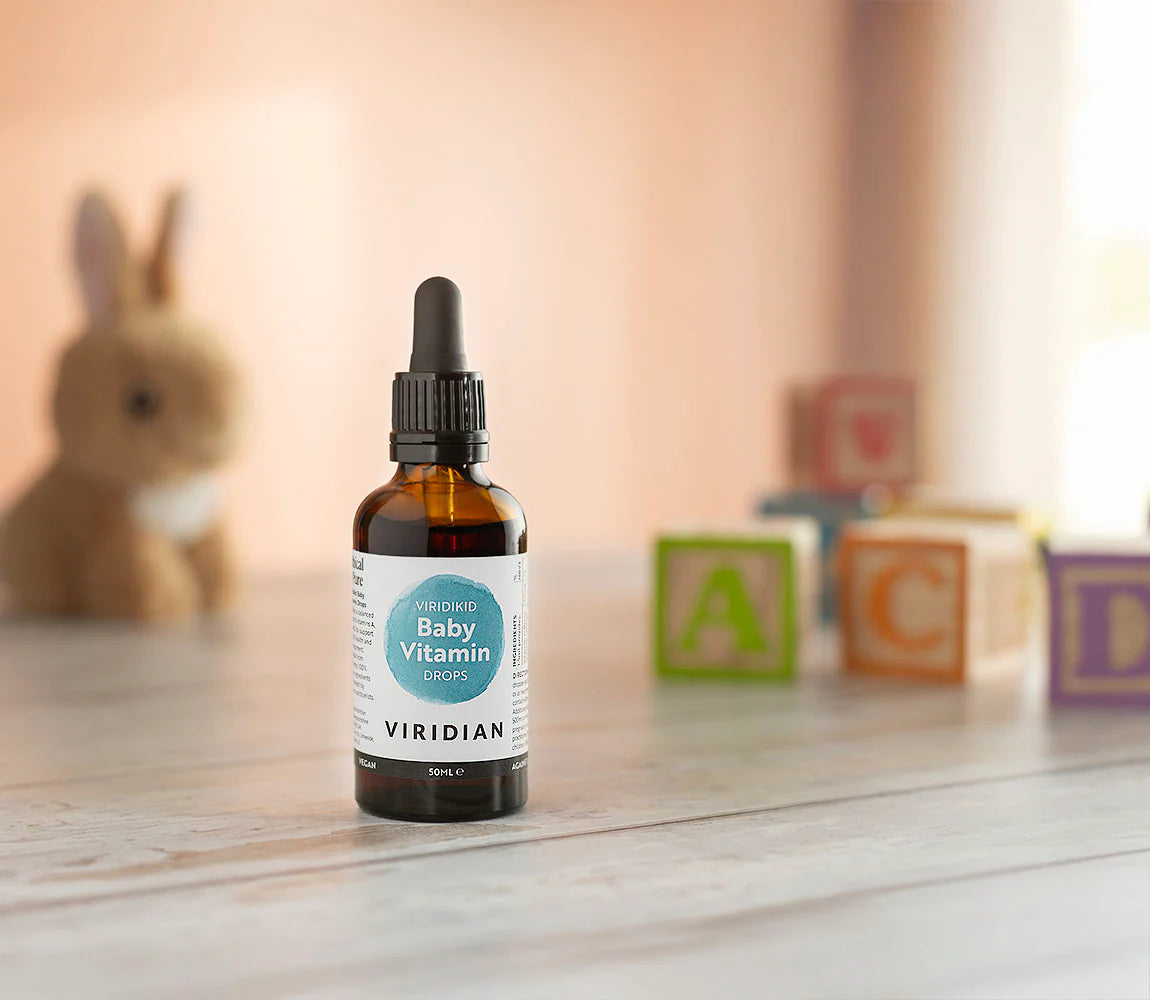 A 50ml bottle of Viridian Baby Vitamin Drops next to its peach-colored retail box featuring a cartoon animal face, on a clean white background.