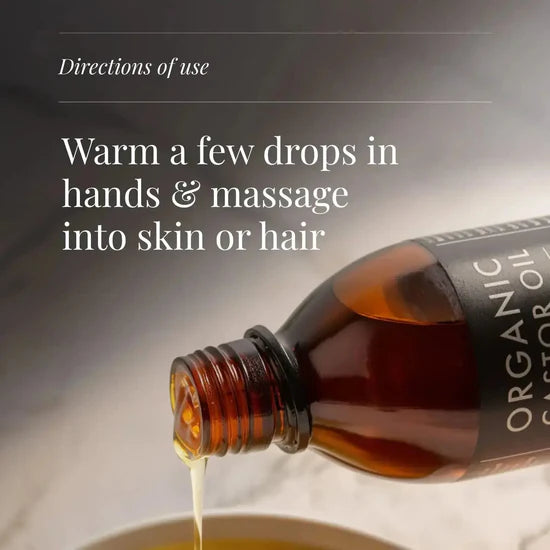 Bottle of organic castor oil with directions for use on a neutral background