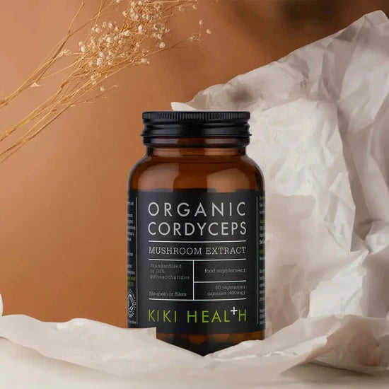 Kiki Health Organic Cordyceps mushroom extract supplement bottle on a soft white background with dried plants.