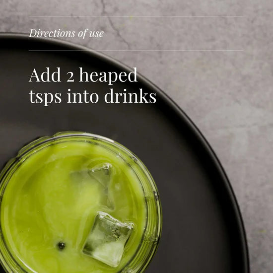 Green drink with ice cubes in a glass on a dark plate, with text on directions of use.