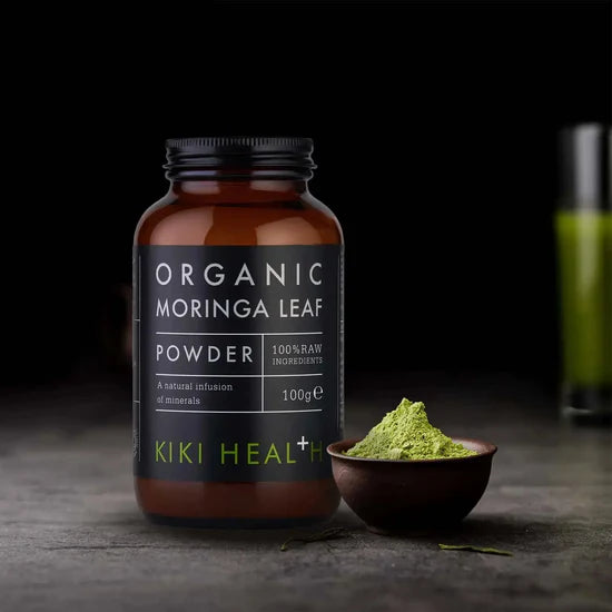 Bottle of Organic Moringa Leaf Powder by KIKI Health with a bowl of powder on a dark background