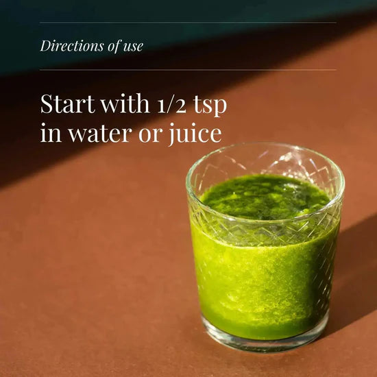 Glass of green liquid on a brown surface with text about directions of use.