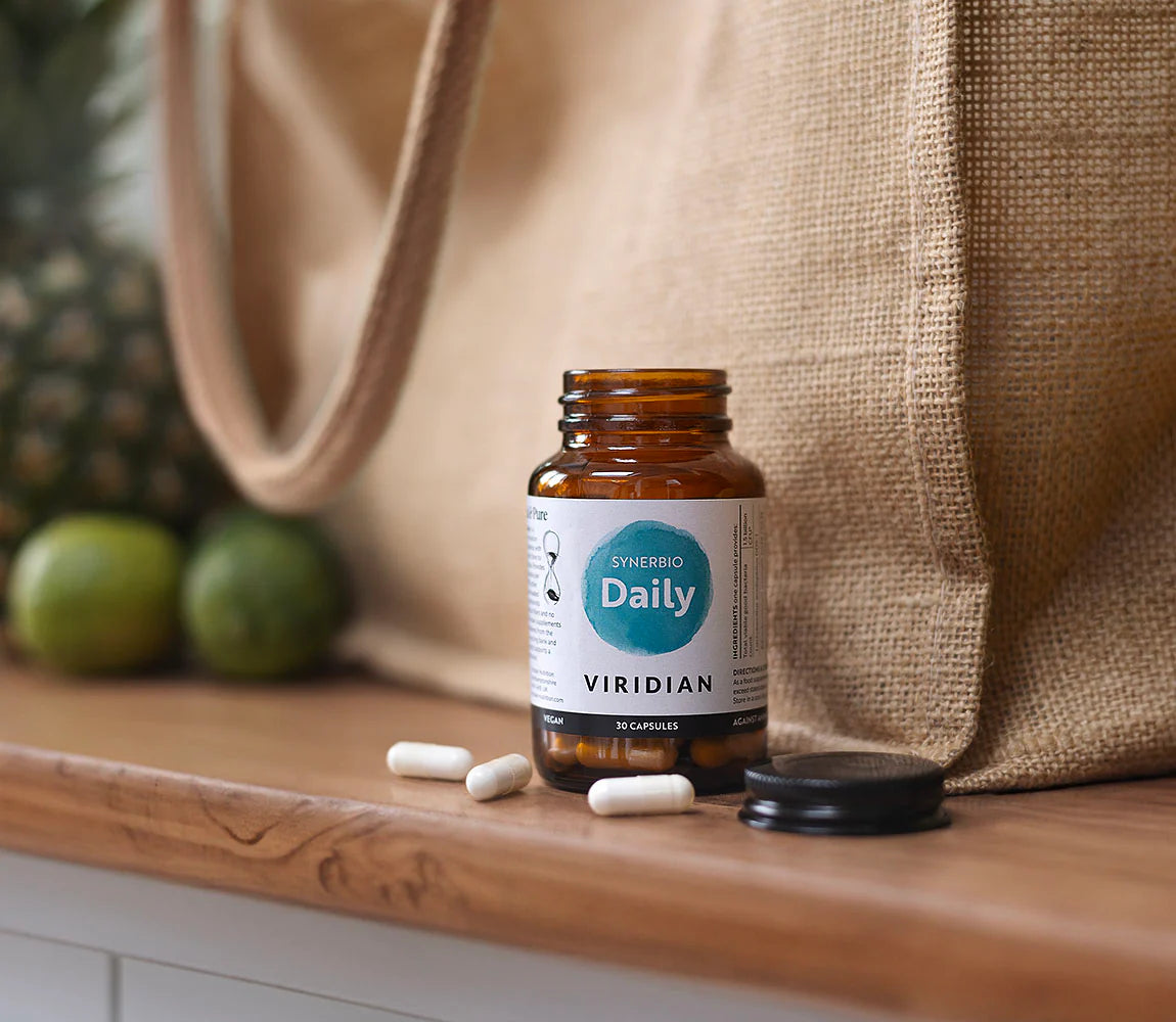 Bottle of Viridian Daily supplement with capsules on a wooden surface