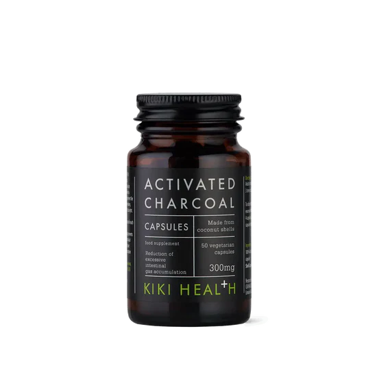 A bottle of Kiki Health Activated Charcoal Capsules on a clean white background. The product is in an amber glass bottle with a black ribbed cap and a black label featuring white text and lime green accents.