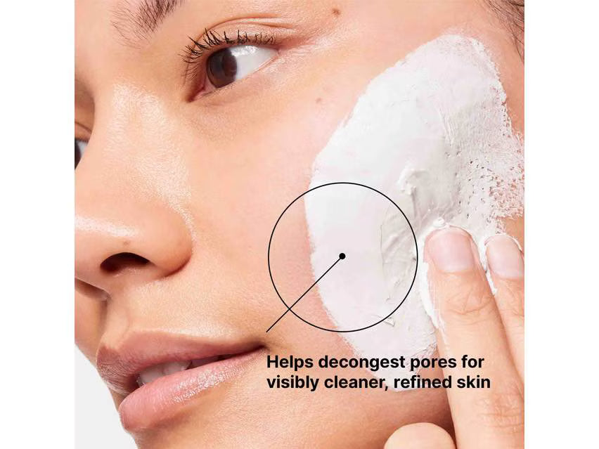 Close-up of a person applying or spreading a white face mask or cream onto one cheek, with a hand and part of the face visible. Text on the image says it helps decongest pores for visibly cleaner, refined skin.