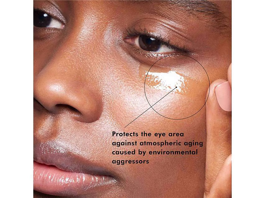 Close-up of a person's face with a circular highlight on the eye area and text reading 'Protects the eye area against atmospheric aging caused by environmental aggressors'.