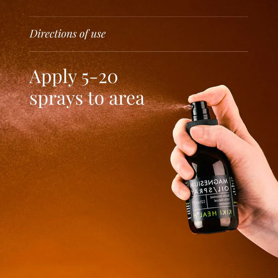 Hand holding a black spray bottle with text on directions of use against a brown background