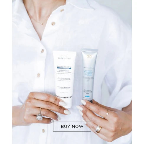 A person in a white button-up shirt holds two skincare tubes, one white and one silver, with a 'BUY NOW' overlay at the bottom.